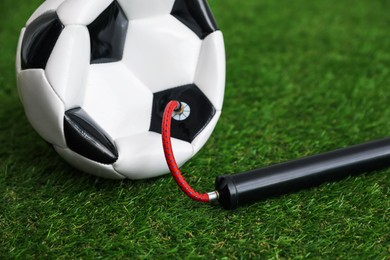 Photo of Soccer ball and manual air pump on artificial grass, closeup