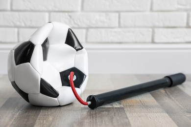 Photo of Soccer ball and manual air pump indoors, closeup