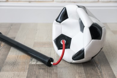 Photo of Soccer ball and manual air pump indoors, closeup