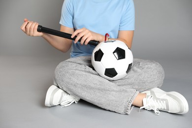 Photo of Woman inflating soccer ball with manual air pump on grey background, closeup