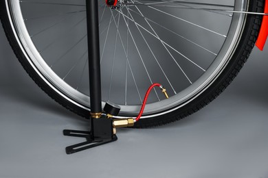 Photo of Bicycle and manual air pump on grey background, closeup
