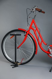 Photo of Bicycle and manual air pump on grey background, closeup