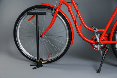 Photo of Bicycle and manual air pump on grey background, closeup