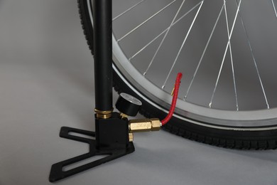 Photo of Bicycle and manual air pump on grey background, closeup