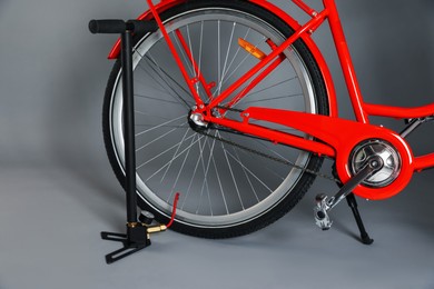 Photo of Bicycle and manual air pump on grey background, closeup