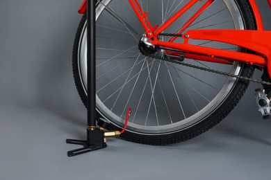 Photo of Bicycle and manual air pump on grey background, closeup