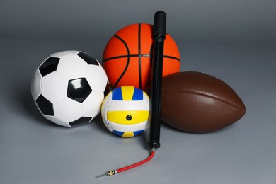 Photo of Different balls and manual air pump on grey background