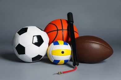 Photo of Different balls and manual air pump on grey background