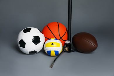 Photo of Different balls and manual air pump on grey background