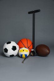 Photo of Different balls and manual air pump on grey background