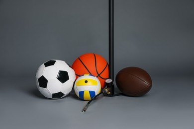 Photo of Different balls and manual air pump on grey background