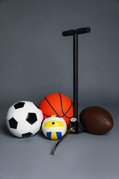Photo of Different balls and manual air pump on grey background