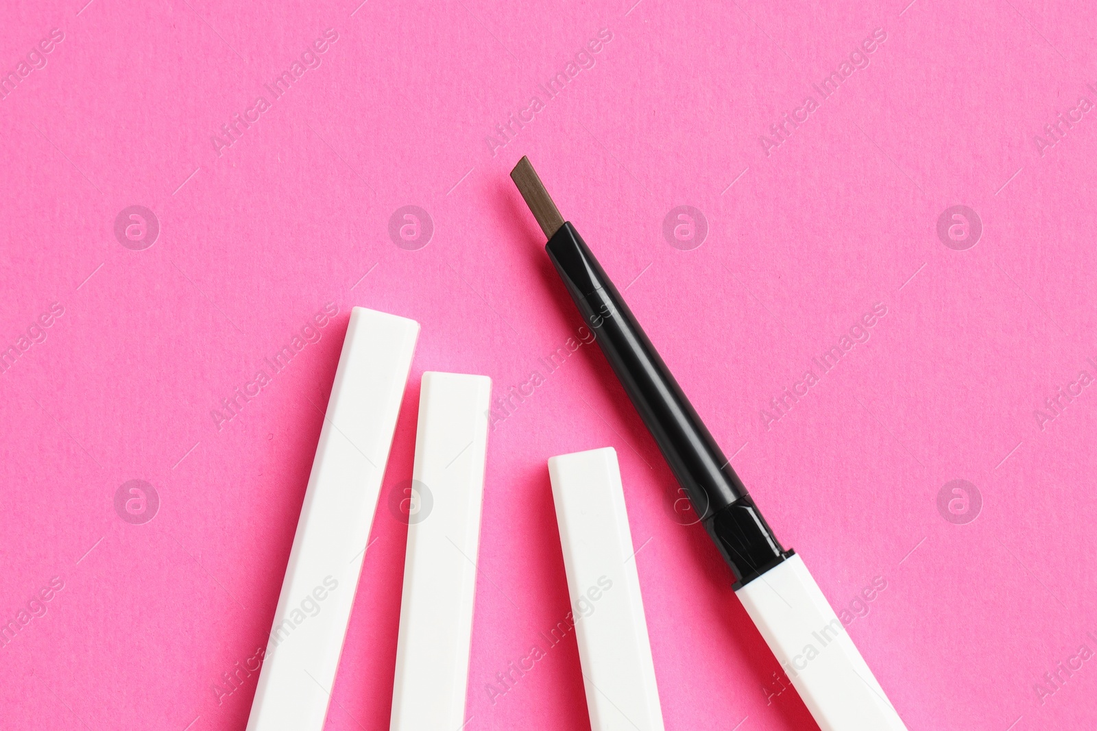 Twist up eyebrow pencils on bright pink background, flat lay Photo of Twist up eyebrow pencils on bright pink background, flat lay