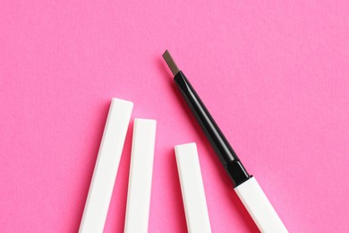 Photo of Twist up eyebrow pencils on bright pink background, flat lay