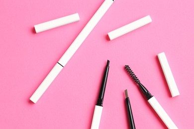 Photo of Twist up eyebrow pencils on bright pink background, flat lay