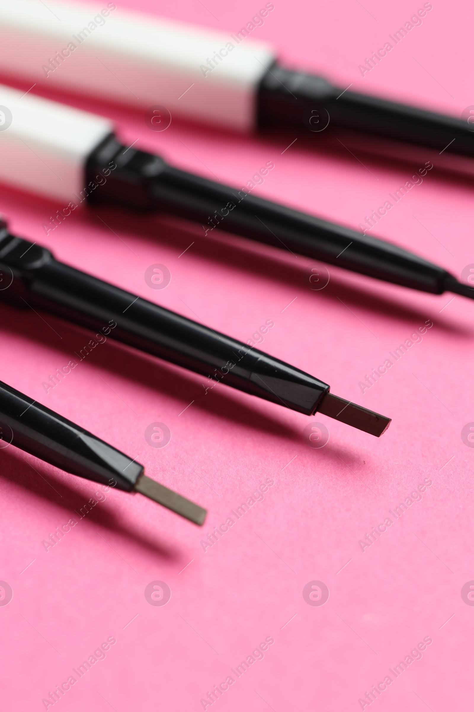 Twist up eyebrow pencils on bright pink background, closeup Photo of Twist up eyebrow pencils on bright pink background, closeup