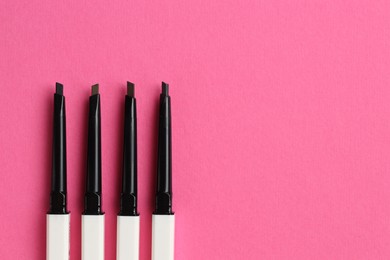 Photo of Twist up eyebrow pencils on bright pink background, flat lay. Space for text
