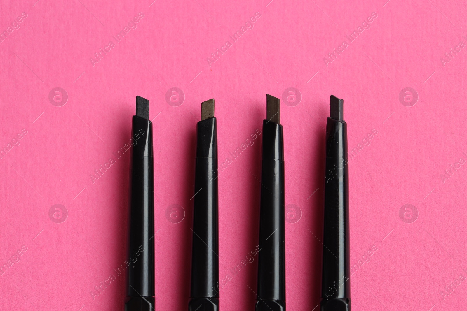 Twist up eyebrow pencils on bright pink background, flat lay Photo of Twist up eyebrow pencils on bright pink background, flat lay