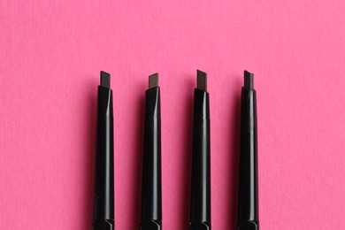 Photo of Twist up eyebrow pencils on bright pink background, flat lay