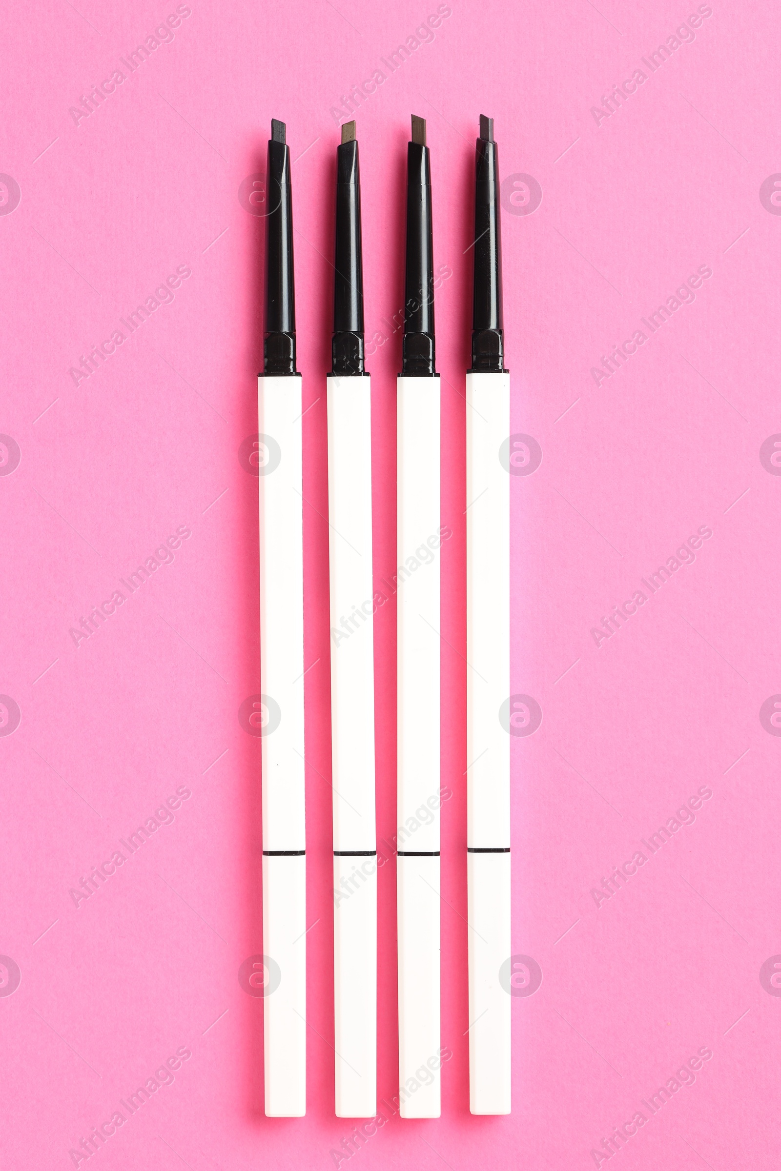 Twist up eyebrow pencils on bright pink background, flat lay Photo of Twist up eyebrow pencils on bright pink background, flat lay