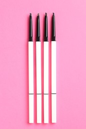 Photo of Twist up eyebrow pencils on bright pink background, flat lay
