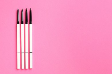 Photo of Twist up eyebrow pencils on bright pink background, flat lay. Space for text