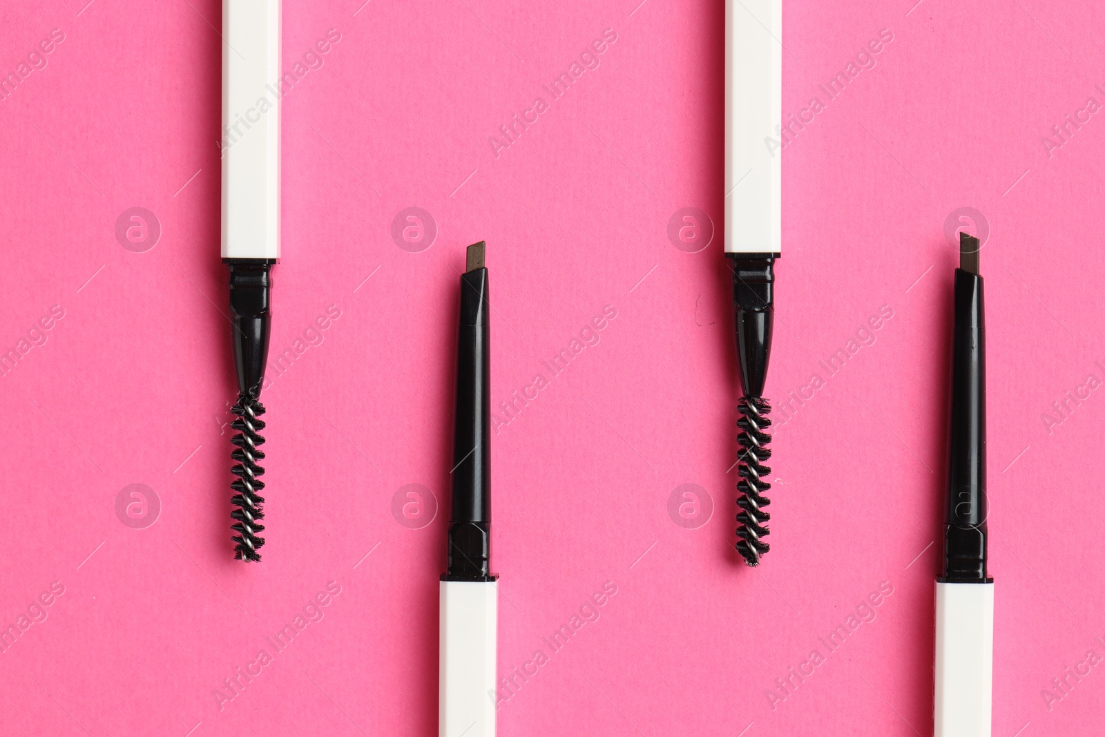 Twist up eyebrow pencils on bright pink background, flat lay Photo of Twist up eyebrow pencils on bright pink background, flat lay