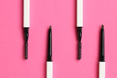 Photo of Twist up eyebrow pencils on bright pink background, flat lay