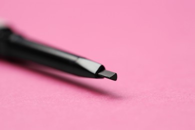 Photo of Twist up eyebrow pencil on bright pink background, closeup. Space for text