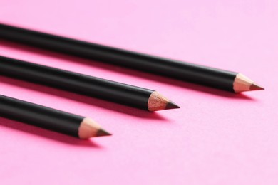 Photo of Different eyebrow pencils on bright pink background, closeup