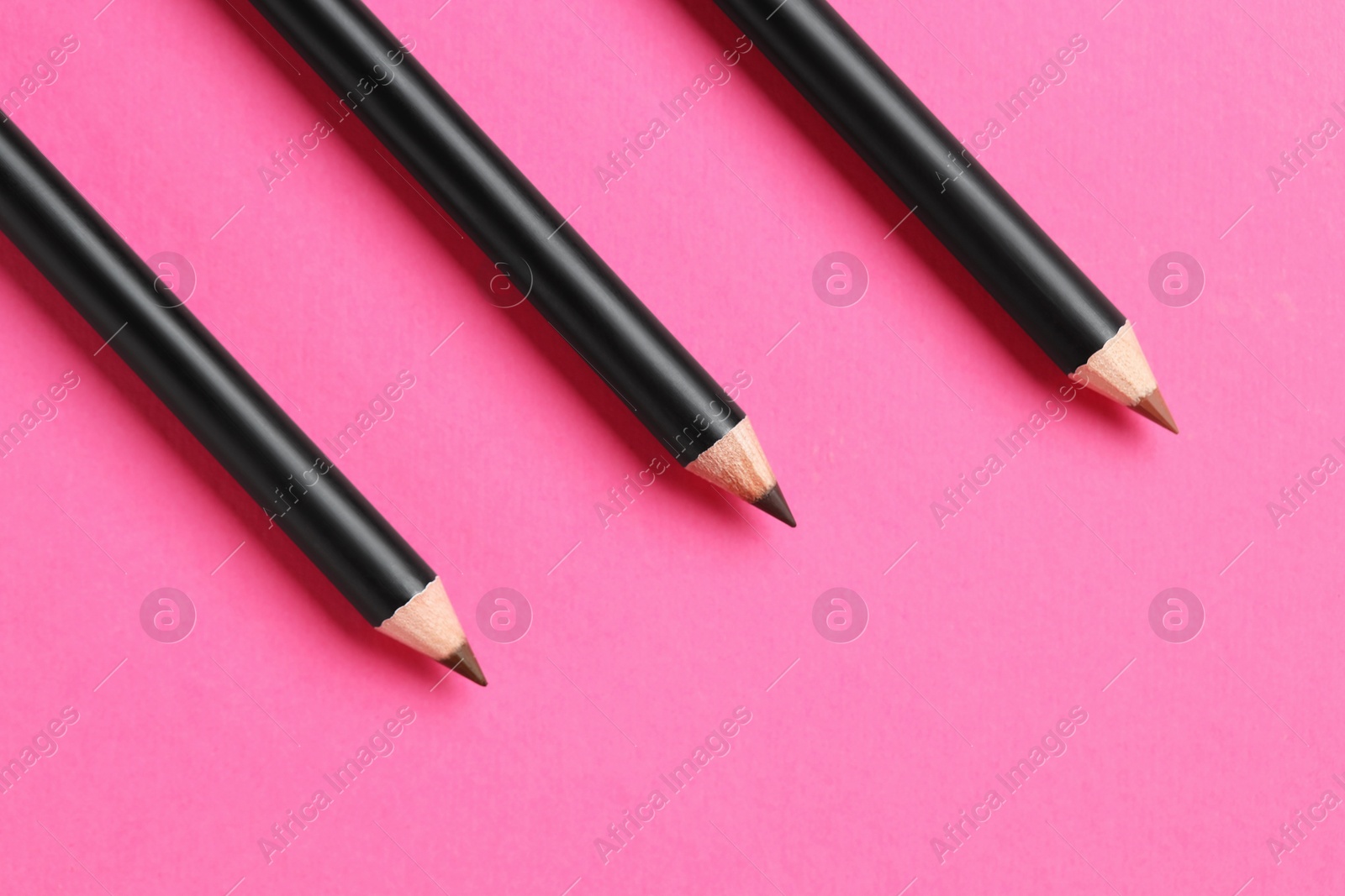 Different eyebrow pencils on bright pink background, flat lay. Space for text Photo of Different eyebrow pencils on bright pink background, flat lay. Space for text