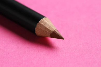 Photo of One brown eyebrow pencil on bright pink background, closeup. Space for text