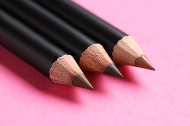 Photo of Different eyebrow pencils on bright pink background, closeup