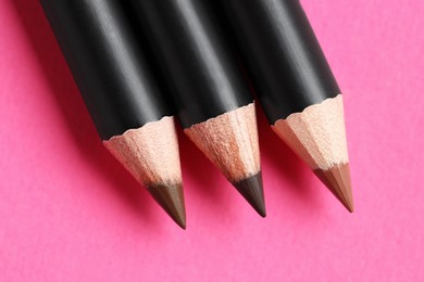 Photo of Different eyebrow pencils on bright pink background, flat lay
