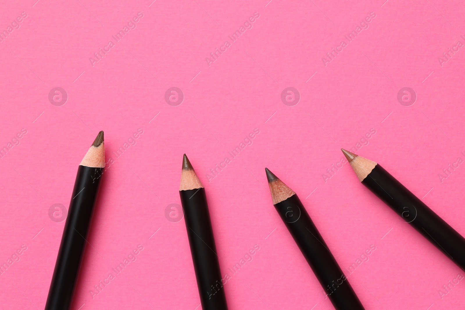 Different eyebrow pencils on bright pink background, flat lay. Space for text Photo of Different eyebrow pencils on bright pink background, flat lay. Space for text