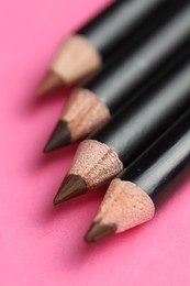 Photo of Different eyebrow pencils on bright pink background, closeup