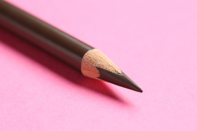 Photo of One brown eyebrow pencil on bright pink background, closeup
