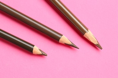 Photo of Different eyebrow pencils on bright pink background, flat lay