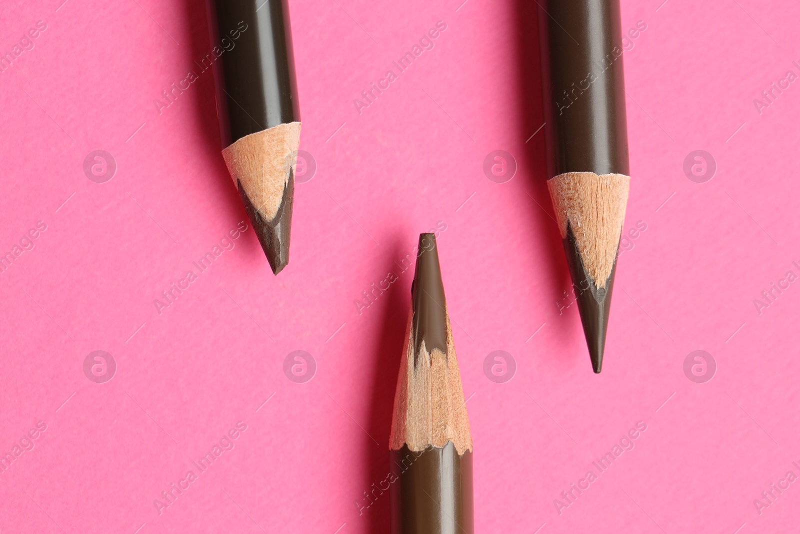 Different eyebrow pencils on bright pink background, flat lay Photo of Different eyebrow pencils on bright pink background, flat lay