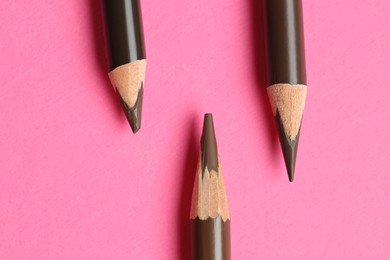 Photo of Different eyebrow pencils on bright pink background, flat lay