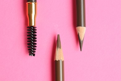 Photo of Different eyebrow pencils on bright pink background, flat lay