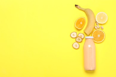 Photo of Superfood. Tasty smoothie in glass bottle and ingredients on yellow background, flat lay. Space for text