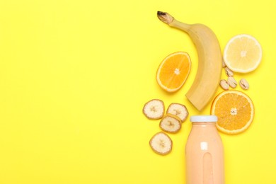 Photo of Superfood. Tasty smoothie in glass bottle and ingredients on yellow background, flat lay. Space for text