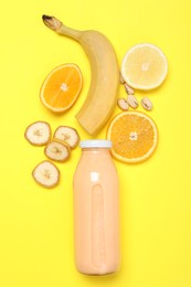 Photo of Superfood. Tasty smoothie in glass bottle and ingredients on yellow background, flat lay