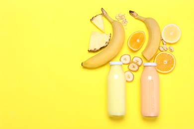 Photo of Superfood. Tasty smoothies in glass bottles and ingredients on yellow background, flat lay. Space for text