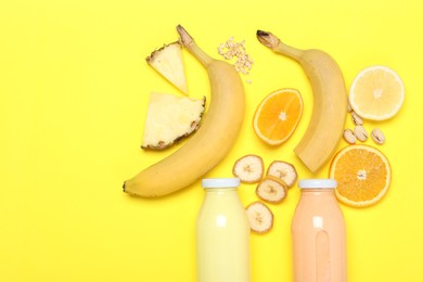 Photo of Superfood. Tasty smoothies in glass bottles and ingredients on yellow background, flat lay. Space for text