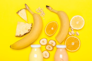 Photo of Superfood. Tasty smoothies in glass bottles and ingredients on yellow background, flat lay