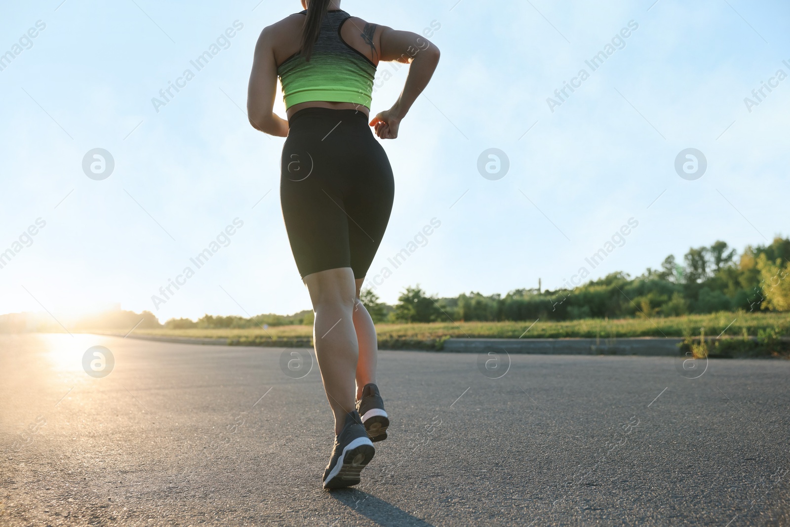 Woman in sportswear running on road outdoors, closeup Photo of Woman in sportswear running on road outdoors, closeup