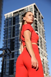 Photo of Beautiful woman in sportswear before running near building outdoors, low angle view