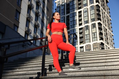 Photo of Beautiful woman in sportswear before running on stairs near buildings outdoors, low angle view